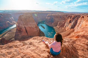 Rear view of a young woman enjoying a view of the incredible Horseshoe Bend, the horseshoe meander...