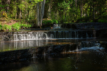 Cascading waterfall cascades in Estonia in green light at summertime