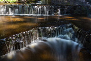 Cascading waterfall cascades in Estonia in green light at summertime