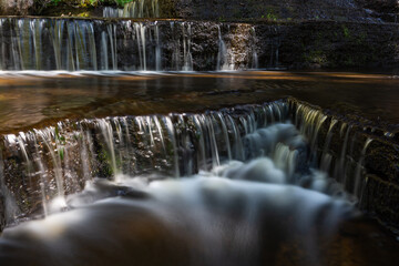 Cascading waterfall cascades in Estonia in green light at summertime