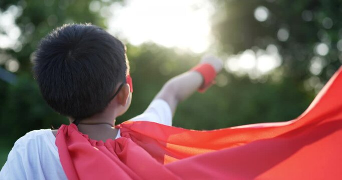 Back of Super hero kid flying outdoor against park