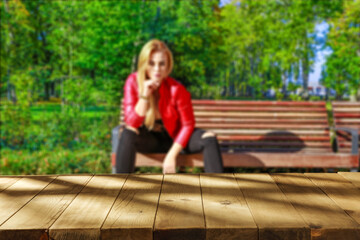 Obraz premium Slim young woman in garden and wooden desk of free space 
