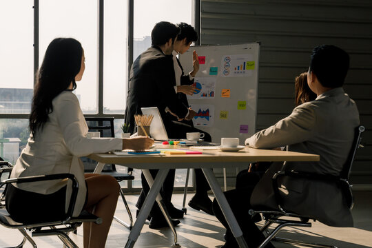 Cute and beautiful Asian businessman holding paper of chart and present information to meeting attendees. Idea for diversity team work