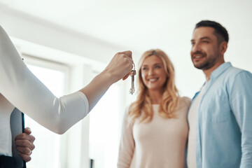 Young beautiful couple in casual wear smiling while receiving keys from new home