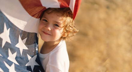 Happy little boy patriot running in the field with American flag