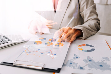 Attractive business woman working in office sitting at desk analyzing statistics holding documents diagrams and charts using laptop at office. smart woman concept.