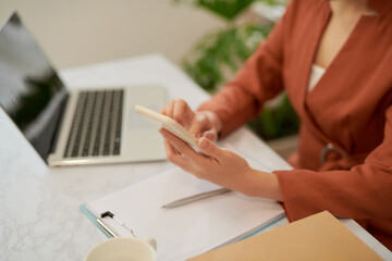 Fototapeta premium Woman using laptop and talking on mobile phone