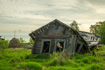 An old, abandoned log house. Deserted village in Russia. A lonely hut without people. Rotten wall construction. Hut against the background of the blue sky. Karelia. Russia. Day.