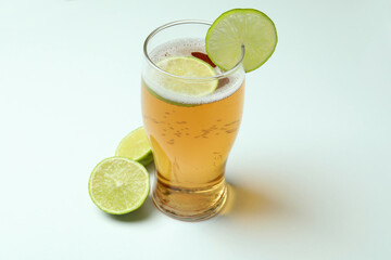 Glass of beer with lime on white background