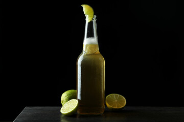 Bottle of beer with lime against black background