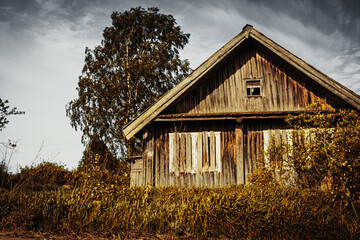 An old, abandoned log house. Deserted village in Russia. A lonely hut without people. Rotten wall construction. Hut against the background of the blue sky. Karelia. Russia. Day.