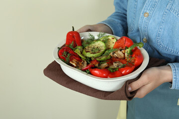 Woman hold grilled vegetables on beige background