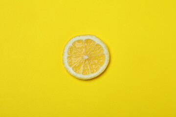 Slice of lemon on yellow background, top view