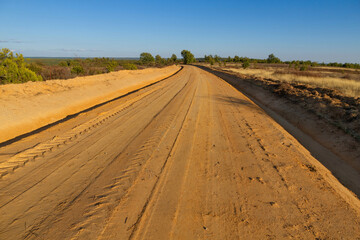 Fototapeta na wymiar Newly prepared dirt road or track in high mountain landscape with scattered oaks 