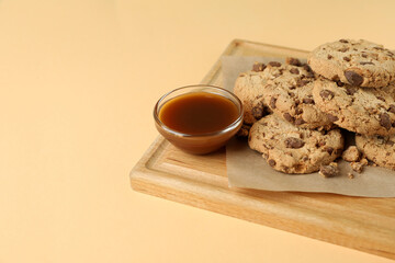 Board with cookies and caramel on beige background