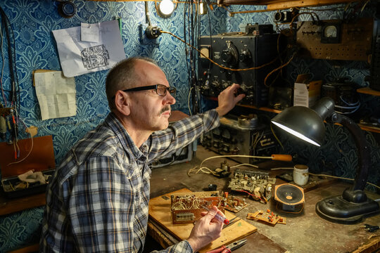 Elderly man repairing an old radio receiver at home