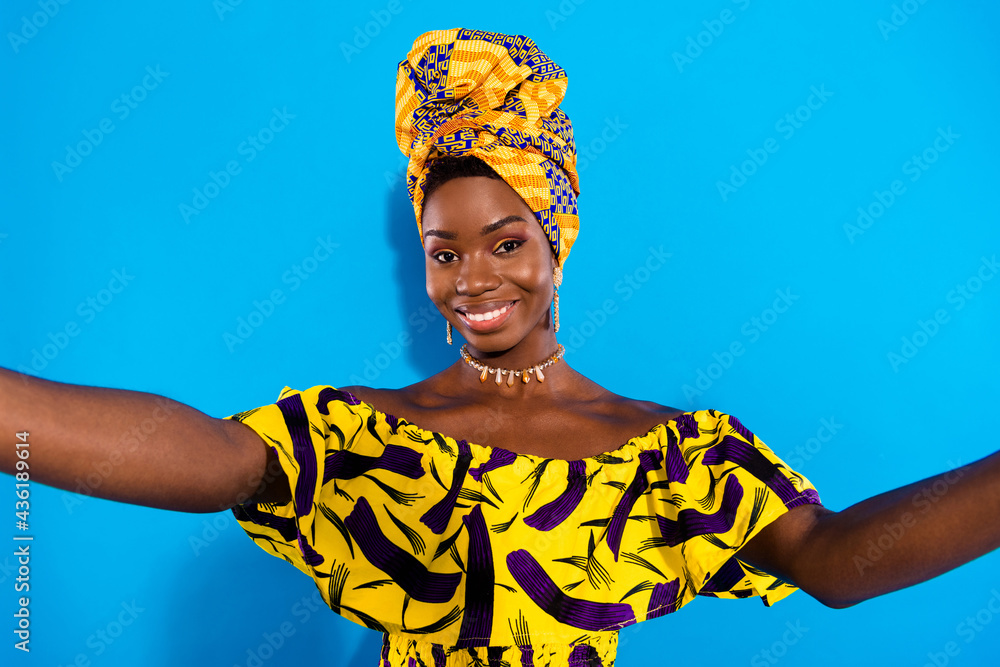 Poster Photo of young smiling cheerful african woman taking selfie wear traditional turban isolated on blue color background