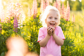 Happy little girl summer in lupin colors, portrait of a blond girl in nature