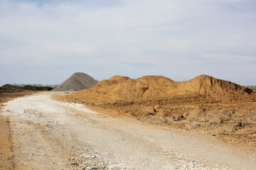 Construction of a new road. A layer of rubble was laid. Nearby are mountains of earth and sand. Close-up. Space for text.