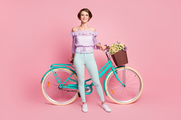Full size photo of young attractive lovely pretty cheerful smiling positive girl with bicycle isolated on pink color background