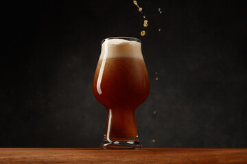 Stream of Stout Beer Pours Into a Beer Glass on a Bar Counter. Glass of Beer on Dark  Background....