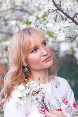 beautiful young blonde woman standing near the apple tree