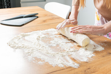 Woman prepares dough on the kitchen table. The chef prepares brad