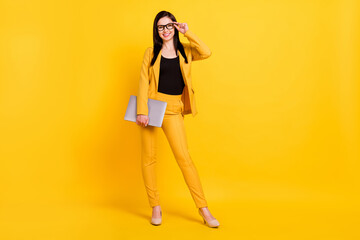 Photo of pretty cute young woman wear formal jacket arm spectacles holding modern gadget smiling isolated yellow color background