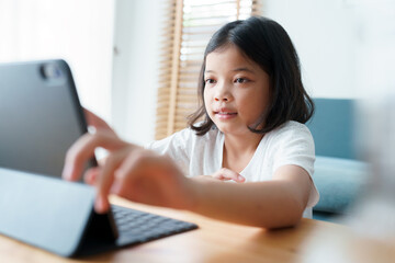 Asian little girl learning online via the internet tutor on a tablet