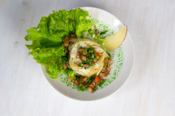 Tagliatelle nest with beshame sauce garnished with tomato, dill, lettuce in bowl on white background