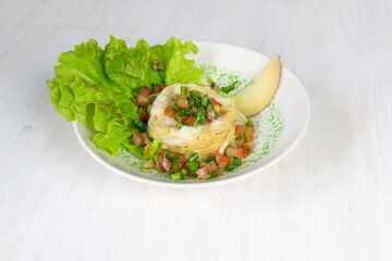 Tagliatelle nest with beshame sauce garnished with tomato, dill, lettuce in bowl on white background