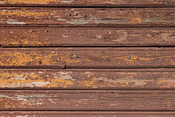 Old cracked brown and yellow paint on wood planks