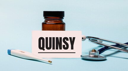 On a blue background - a bottle for pills, a stethoscope, an electronic thermometer and a card with...