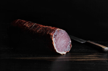 Traditionally smoked Iberian pork loin on rustic wooden table. - obrazy, fototapety, plakaty