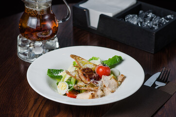 Chicken caesar salad cheese and bacon on a brown wood table