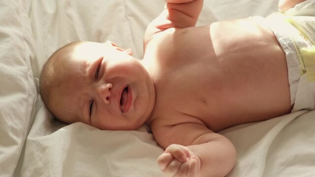 Little baby newborn crying, cry scream, cries loudly. New born child tired and hungry in bed on white blanket. Infant screaming. Healthy little kid shortly after birth. Portrait. Infancy, babyhood.