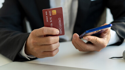 Businessmen holding credit cards and using laptops and phones shop online and pay via the Internet.