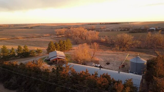 Aerial Forward Panning Shot Of Houses In Agricultural Field During Sunset Against Cloudy Sky - Oakley, Kansas