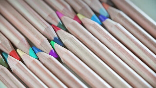 Video of colorful pencils close-up lie flat. Background wooden pencils.