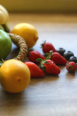 Straw bag full of various colorful fruit on wooden background. Selective focus.