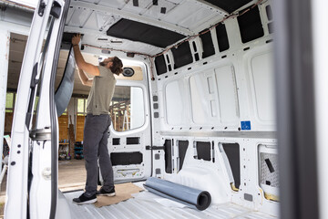 Man puts thermal insulation on the inside of a van
