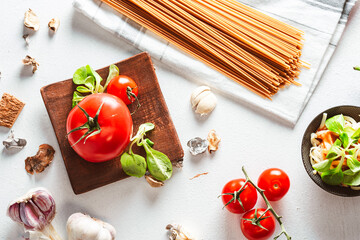 Juicy tomato with pasta and vegetables on bright background. Spaghetti base. - obrazy, fototapety, plakaty