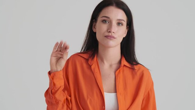 A displeased woman is showing blablabla sign showing nonsense content something standing isolated over grey wall in the studio
