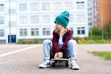 Little blonde girl on a skateboard in the city