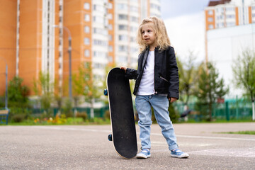 Little blonde girl on a skateboard in the city