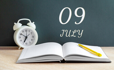 july 09. 09-th day of the month, calendar date.A white alarm clock, an open notebook with blank pages, and a yellow pencil lie on the table.Summer month, day of the year concept