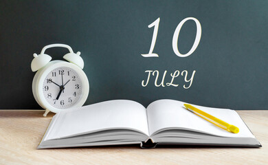 july 10. 10-th day of the month, calendar date.A white alarm clock, an open notebook with blank pages, and a yellow pencil lie on the table.Summer month, day of the year concept