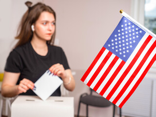 American flag next to a girl voter. The American voter is blurred. Concept - voting during the US...