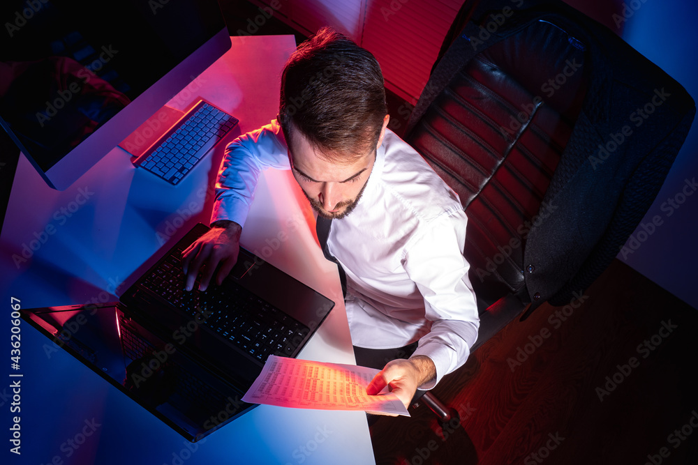 Poster office worker works in a dark office. a man working at a computer top view. concept - office worker 