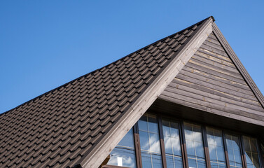 Brown corrugated metal profile roof installed on a modern house. The roof of corrugated sheet. Roofing of metal profile wavy shape. Modern roof made of metal. Metal roofing.